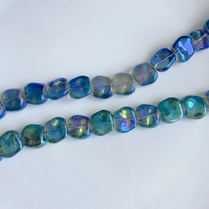 Close-up of iridescent blue-green square glass beads with rainbow coating for DIY jewelry
