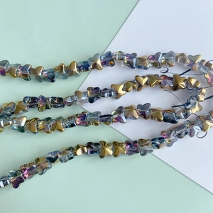 Macro detail of iridescent glass butterfly beads with gradient electroplated finish