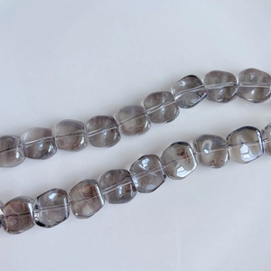 Close-up of translucent smoky gray square glass beads with a shimmering laser finish