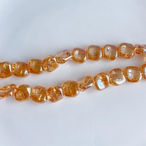 Macro view of amber iridescent laser cut glass square beads for DIY jewelry making