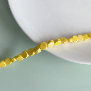 Macro shot of glossy yellow flat round ceramic beads for DIY necklace jewelry making