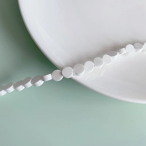 Macro shot of white ceramic flat round beads for DIY jewelry making accessories
