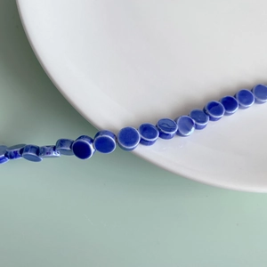 Macro detail of dark blue ceramic flat round beads for DIY handmade jewelry crafts