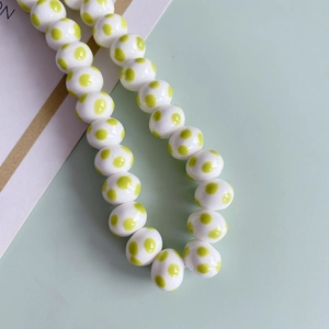 Dettaglio di perle in ceramica bianche con pois verdi per creazione gioielli fai da te