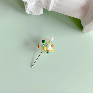 Detailed view of DIY colorful polka dot glass bead pin with white pearl accent