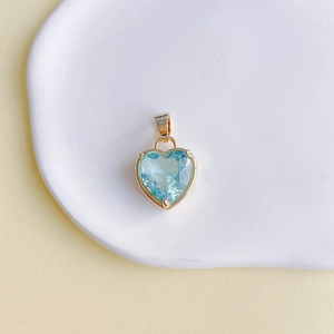 Détail macro d'un pendentif en pierre en forme de cœur bleu clair avec base en cuivre doré