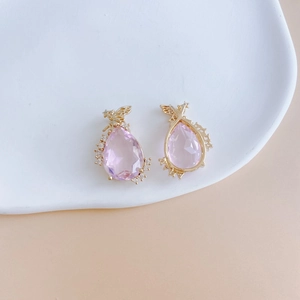 Detail of pink teardrop zircon earrings with golden angel wings and micro-pave stones