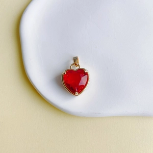 Macro d'un pendentif coeur en pierre rouge avec bordure en cuivre doré sur un plateau