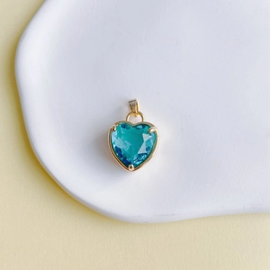 Gros plan d'un pendentif en pierre cyan en forme de cœur avec sertissage doré