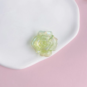 Macro detail of a translucent green iridescent acrylic rose flower flatback DIY accessory