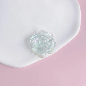 Macro view of iridescent acrylic rose flower charm on white ceramic display plate