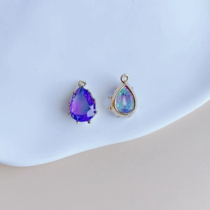 Détail de pendentifs en cristal goutte violet et aurore avec sertissage à griffes dorées