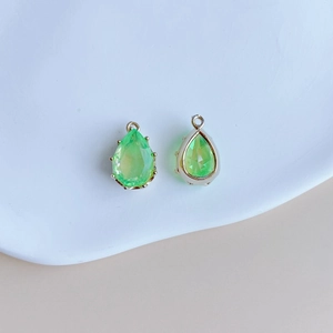 Détail macro de pendentifs en cristal vert clair taillés en poire avec serti à griffes doré