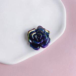 Detailed top view of purple iridescent acrylic rose flower charm on white tray