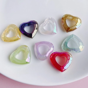 Macro view of colorful faceted acrylic heart charms in a ceramic dish for DIY jewelry