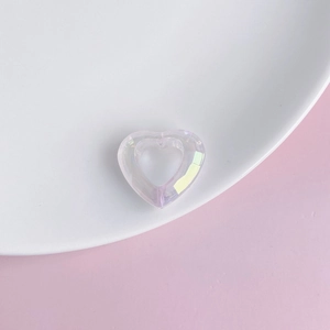 Close-up of iridescent hollow heart pendant made of faceted acrylic resin on white plate