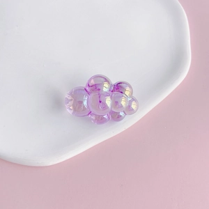 Macro detail of purple iridescent chubby cloud charm with aurora finish on ceramic tray