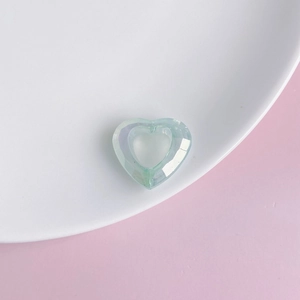Close-up of light blue faceted acrylic heart pendant with hollow center on white plate