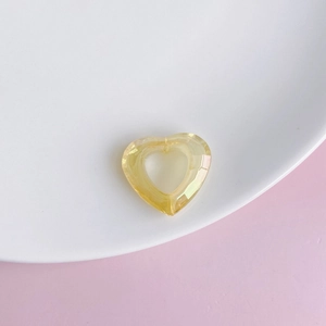 Close-up of faceted hollow heart acrylic pendant in amber yellow for DIY jewelry
