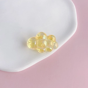 Macro shot of a yellow translucent chubby cloud acrylic charm with laser iridescent gloss