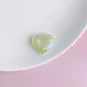 Macro shot of light green iridescent acrylic heart pendant with hollow center for DIY jewelry