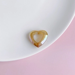 Detailed view of iridescent amber resin hollow heart charm with faceted cutting