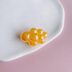 Macro view of chubby orange translucent acrylic cloud charm with smooth pearlescent finish