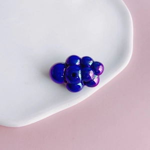 Detail of blue-purple iridescent acrylic cloud bead with hole on white ceramic plate