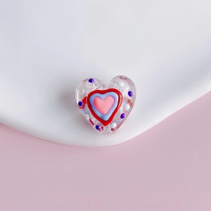 Macro detail of a heart-shaped DIY transparent bead with nested colorful patterns and dots