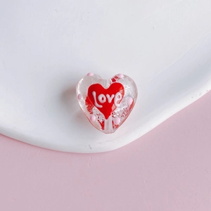 Macro view of transparent heart bead with love engraving and pink polka dots