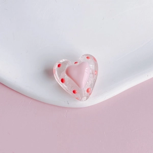 Macro detail of heart-shaped acrylic beads with red polka dots for DIY jewelry making