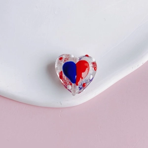 Macro view of transparent heart-shaped bead with red and blue pattern for DIY jewelry