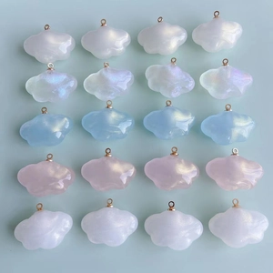 Détail macro de pendentifs nuages en résine nacrée irisés avec boucles dorées pour bijoux DIY