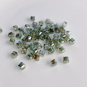 Macro view of faceted cube glass beads with iridescent olive green finish and center hole
