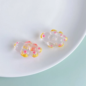 Close-up of translucent acrylic cloud charms with pink dots and yellow outlines