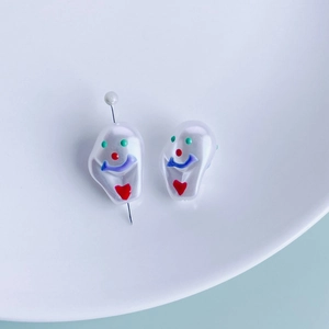Macro detail of hand-painted funny clown faces on irregular resin pearl DIY pendants