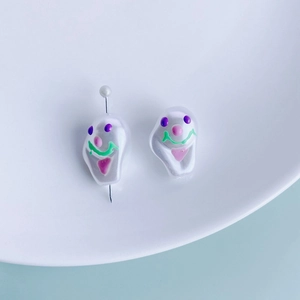 Macro detail of acrylic resin pendants with funny hand-painted clown faces for DIY jewelry