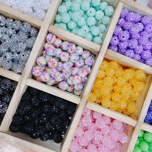 Perles colorées en résine et strass pour bijoux DIY exposées dans un plateau en bois