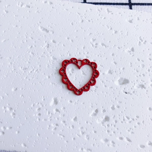 Close-up of bright red heart pendant with hollow heart patterns for DIY jewelry making