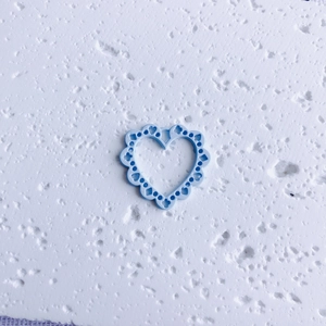 Close-up of light blue hollow heart charm with intricate lace edges for DIY jewelry making
