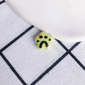 Macro view of handmade yellow-green ceramic cat paw pendant with glossy finish