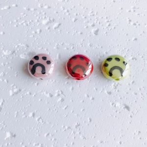 Detailed view of pink, red and green ceramic beads with black paw print patterns