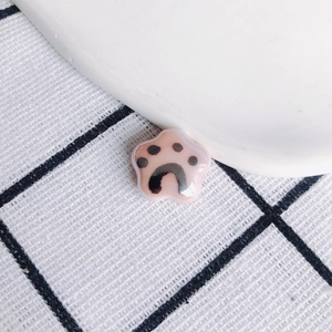 Macro shot of a glossy pink star-shaped ceramic pendant featuring a black cat paw print