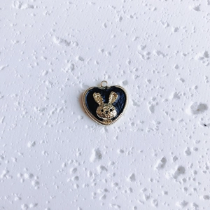 Detail of heart pendant with golden rabbit relief on black enamel background
