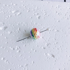 Macro shot of colorful striped aurora bubble bead with pearl pin for DIY jewelry crafts