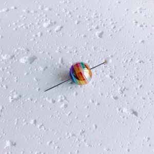 Macro detail of a colorful striped acrylic bead on a metal pin for DIY jewelry making