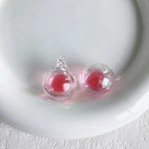 Detail von irisierenden Perlen für Schmuck mit rosafarbenem Kern und Aufhängeschlaufe