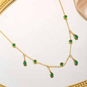 Gold titanium steel necklace with green zircon waterdrop pendants on a mirror
