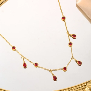 Detail of gold titanium chain with vibrant red teardrop zircon and round cut gemstones