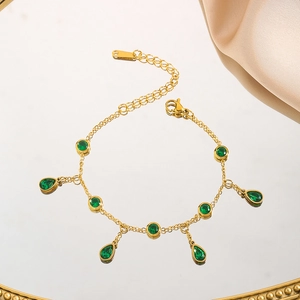 Elegant gold titanium steel bracelet with green zircon teardrop pendants on a mirror tray
